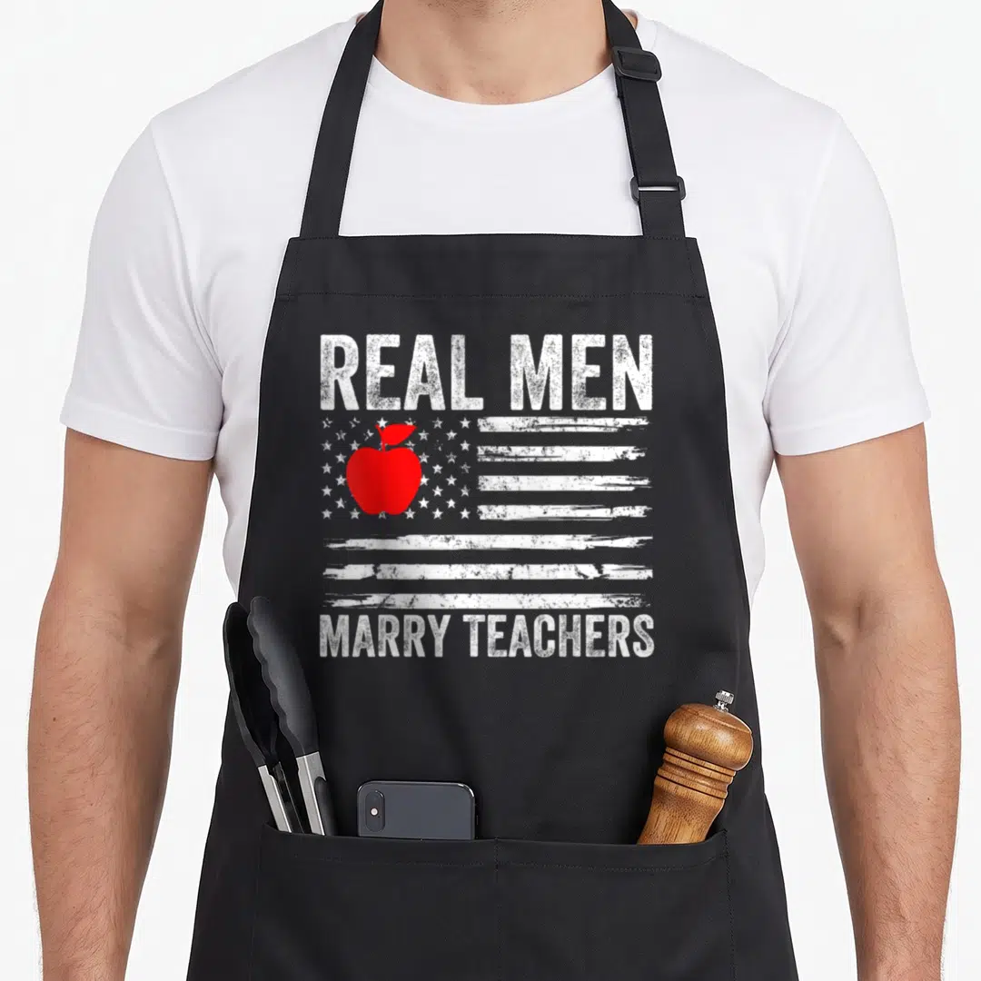 Husband teacher pocket apron - Distressed flag with red apple and text Real Men Marry Teachers — shown on a black cotton canvas apron against a white background