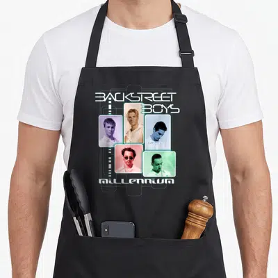 Backstreet novelty apron - Backstreet Boys Millennium text above and below five colored portrait frames in retro style — shown on a black cotton canvas apron against a white background