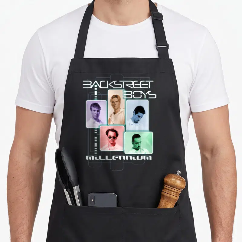 Backstreet novelty apron - Backstreet Boys Millennium text above and below five colored portrait frames in retro style — shown on a black cotton canvas apron against a white background