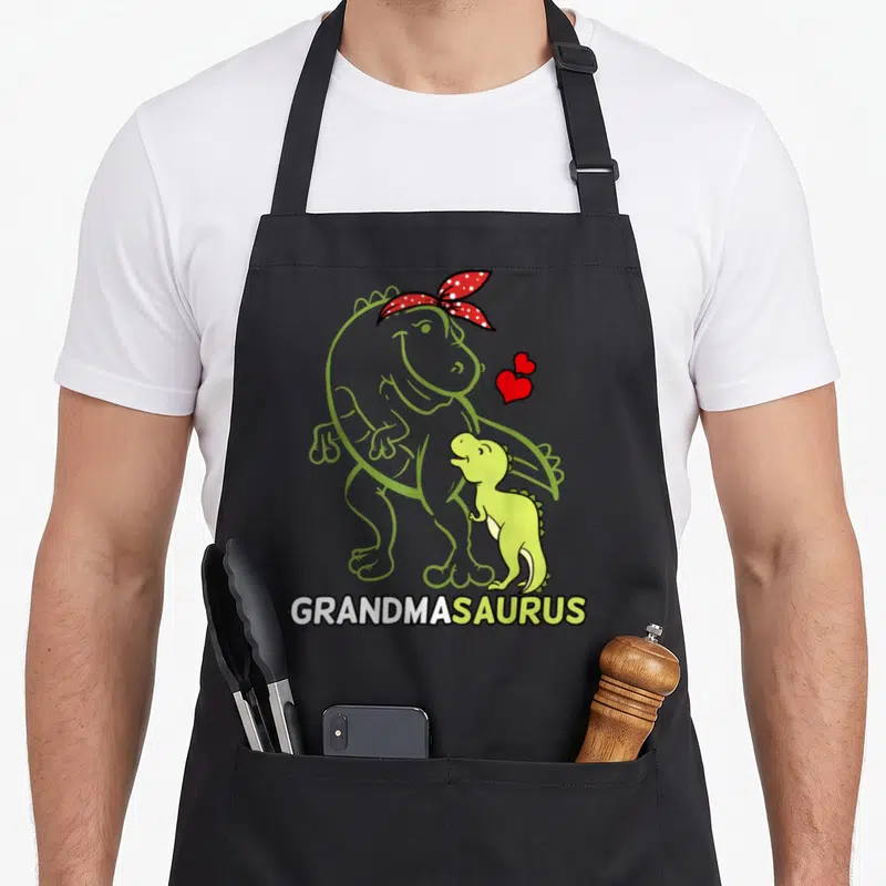 Grandmasaurus mother's day aprons - Lime green dinosaur outline with red bandana and smaller dino above GRANDMASAURUS — shown on a black cotton canvas apron against a white background