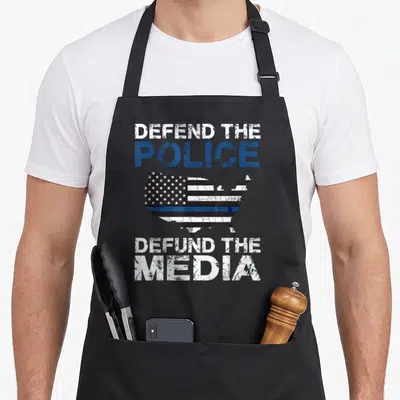 Defend police apron - Distressed USA map with thin blue line and text Defend The Police Defund The Media — shown on a black cotton canvas apron against a white background