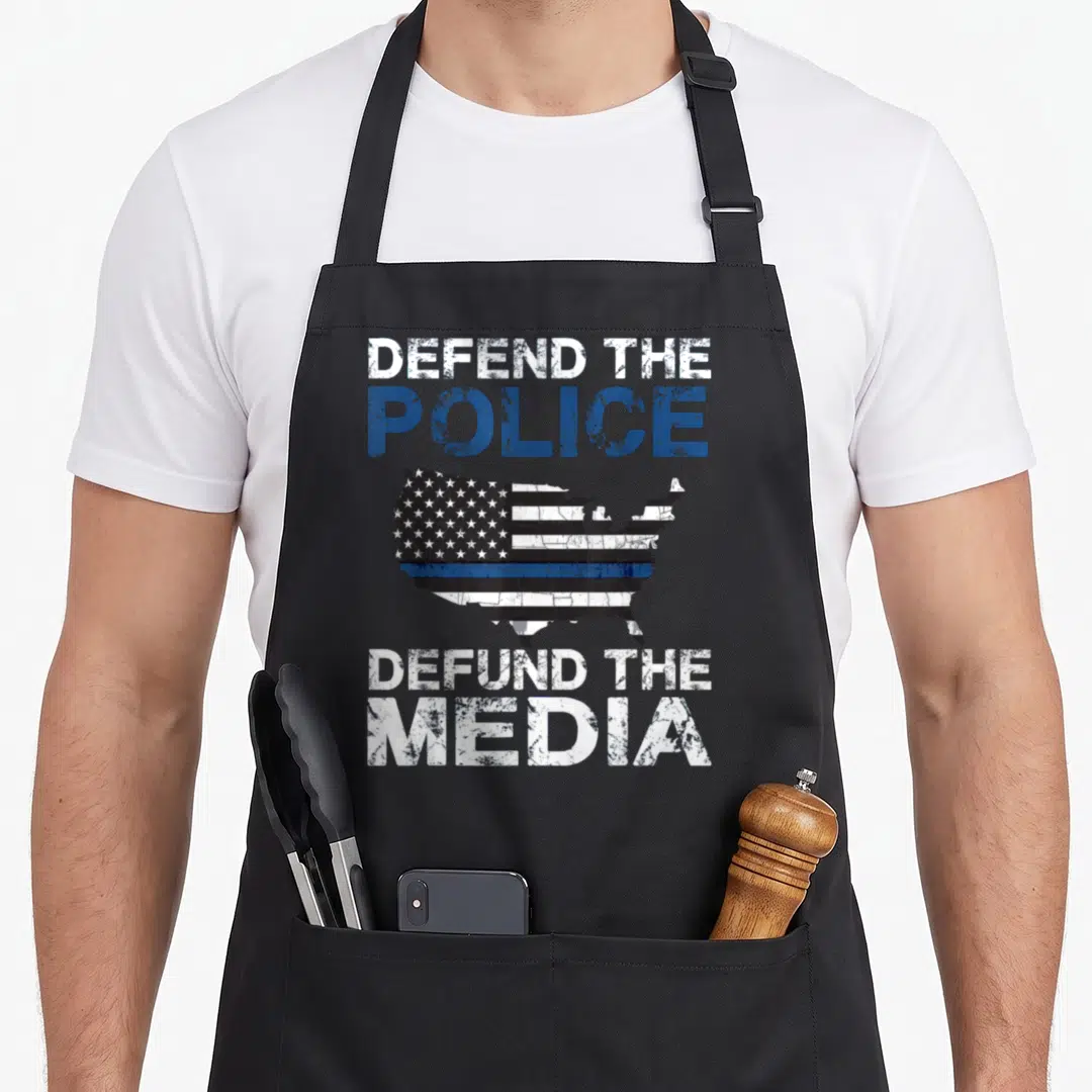Defend police apron - Distressed USA map with thin blue line and text Defend The Police Defund The Media — shown on a black cotton canvas apron against a white background