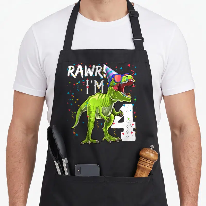 Rawr 4th t rex apron - Green T-Rex with sunglasses and party hat next to white number 4 and confetti — shown on a black cotton canvas apron against a white background