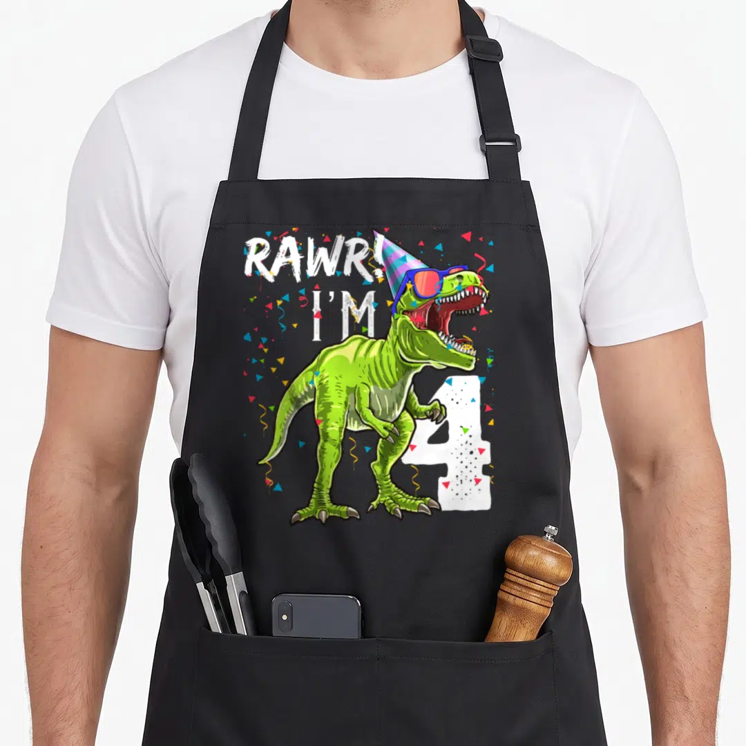 Rawr 4th t rex apron - Green T-Rex with sunglasses and party hat next to white number 4 and confetti — shown on a black cotton canvas apron against a white background