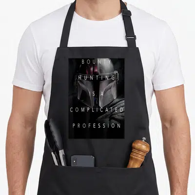 Complicated star war apron - Mandalorian helmet with stacked text bounty hunting is a complicated profession — shown on a black cotton canvas apron against a white background