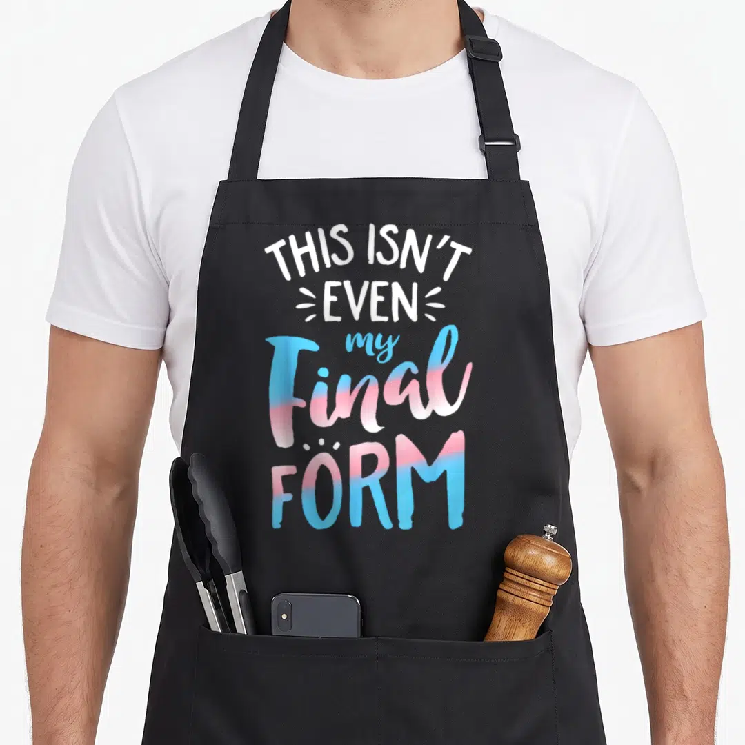 Even pride apron - Stacked text THIS ISN'T EVEN my Final FORM in trans flag blue and pink gradients — shown on a black cotton canvas apron against a white background