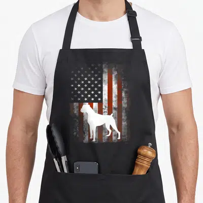 Patriotic boxer dog apron - White Boxer dog silhouette standing in front of a distressed red and white American flag — shown on a black cotton canvas apron against a white background
