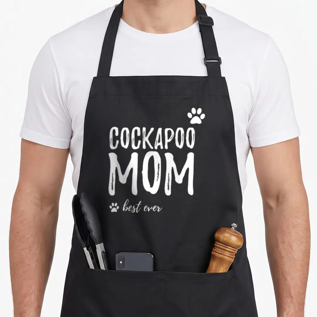 Retro dog cockapoo apron - White COCKAPOO MOM best ever text with three paw prints in typography only style — shown on a black cotton canvas apron against a white background