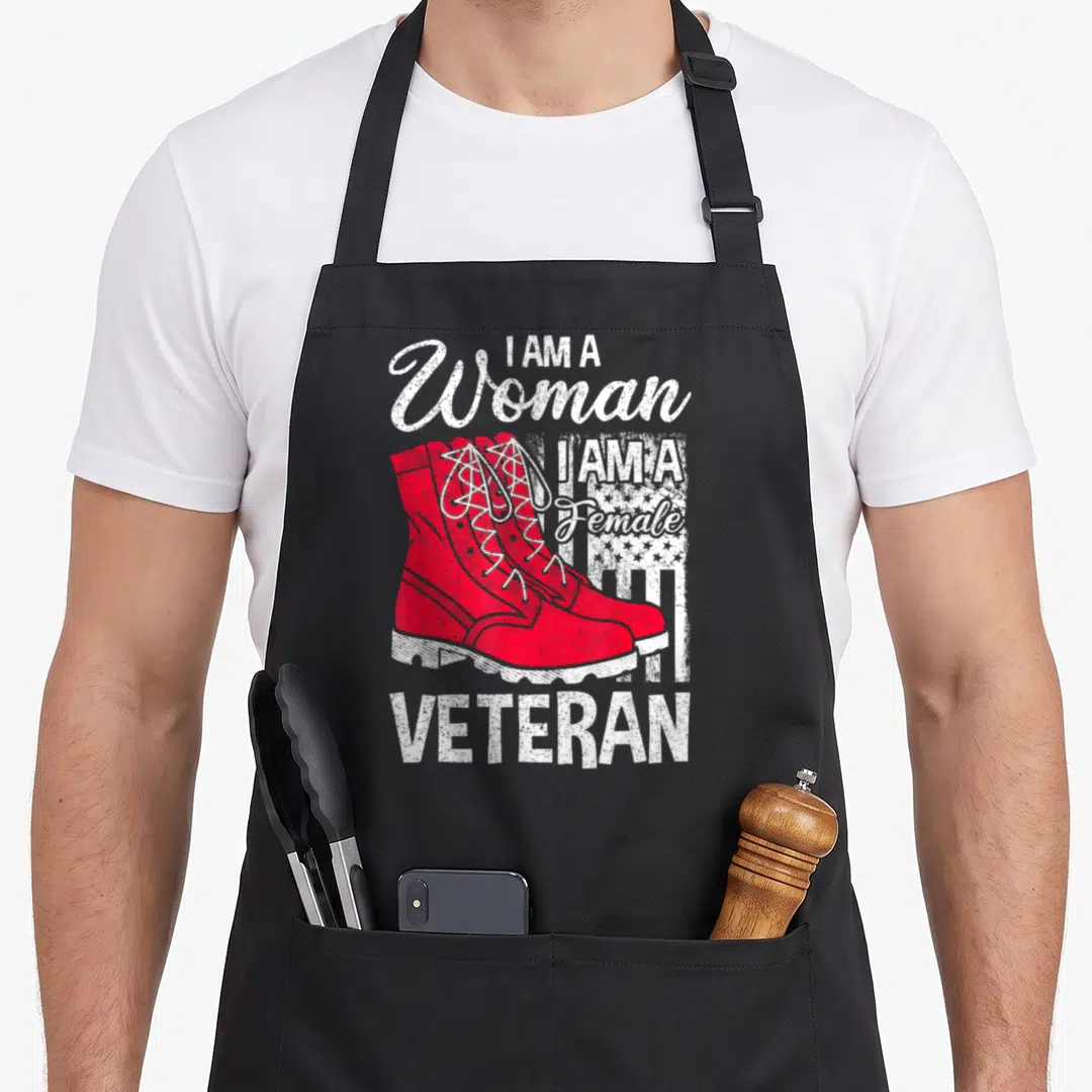 Soldier veteran patriotic apron - Red combat boots with I AM A Woman Female Veteran text and distressed flag pattern — shown on a black cotton canvas apron against a white background