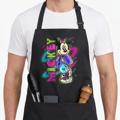 Airbrush crazy mouse man apron - Neon pink and blue Mickey Mouse with vertical MICKEY graffiti text in cartoon style — shown on a black cotton canvas apron against a white background