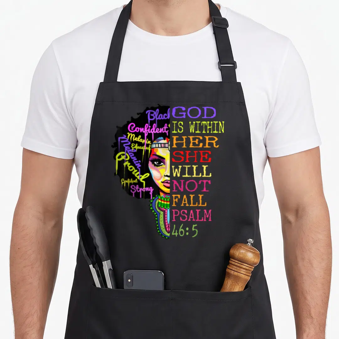 God fall apron - Cartoon woman face with colorful affirming words in hair next to stacked Psalms 46:5 text — shown on a black cotton canvas apron against a white background