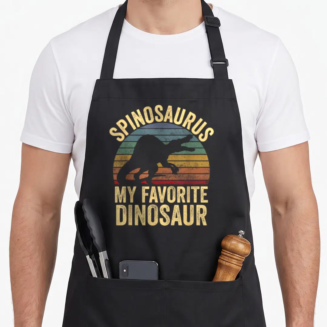 Spinosaurus dino dinosaur apron - Retro striped sun with Spinosaurus silhouette and My Favorite Dinosaur text — shown on a black cotton canvas apron against a white background