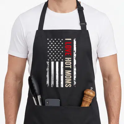 Hot american flag apron - Vertical I Love Hot Moms text over distressed USA flag in red and beige — shown on a black cotton canvas apron against a white background