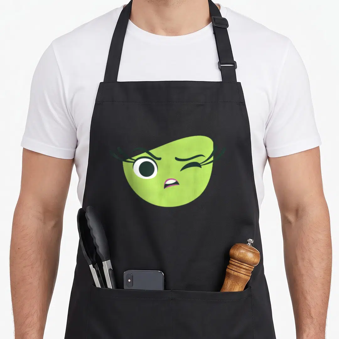 Disgust halloween apron - Lime green cartoon face winking with one open eye and pink lips on canvas — shown on a black cotton canvas apron against a white background