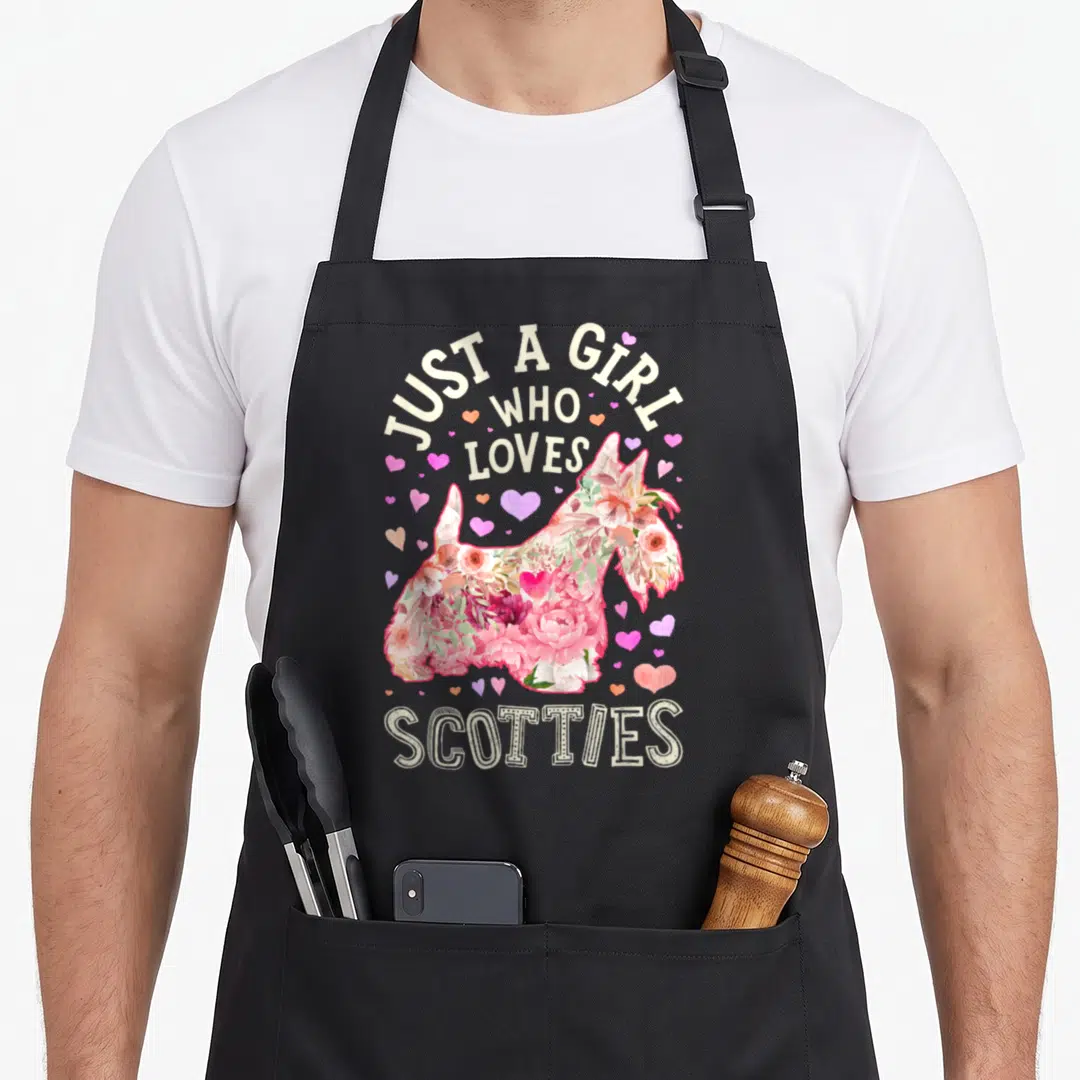 Scottie scottish dog apron - Floral Scottish Terrier silhouette surrounded by pink and purple hearts with cream text — shown on a black cotton canvas apron against a white background