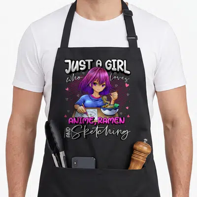Cute anime japan apron - Girl with purple hair eating ramen and sketching with stacked text and hearts — shown on a black cotton canvas apron against a white background