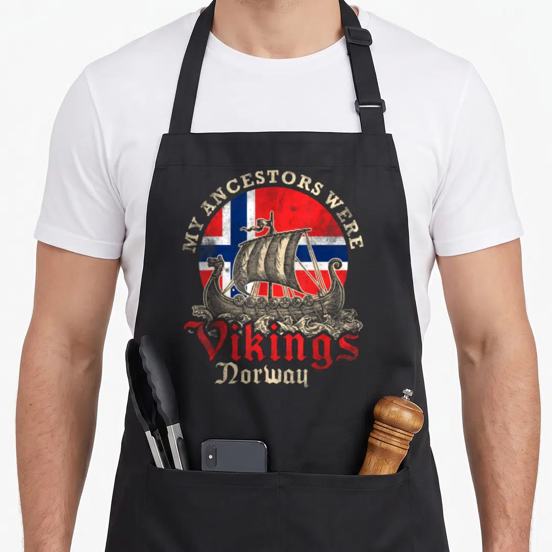 Ship norwegian kitchen aprons - Viking ship on waves in front of circular Norwegian flag with distressed text MY — shown on a black cotton canvas apron against a white background