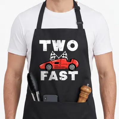 Fast 2nd apron - Red race car with two checkered flags between white TWO FAST text — shown on a black cotton canvas apron against a white background