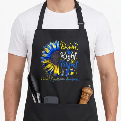 Right sunflower apron - Blue yellow sunflower with Down Right Perfect text and socks on line — shown on a black cotton canvas apron against a white background