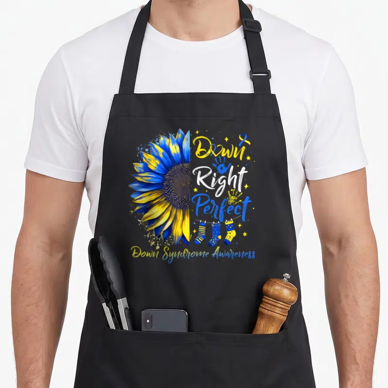 Right sunflower apron - Blue yellow sunflower with Down Right Perfect text and socks on line — shown on a black cotton canvas apron against a white background