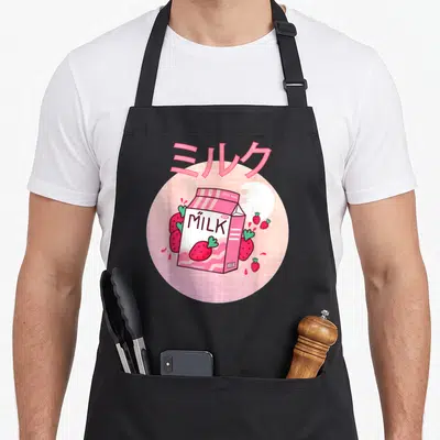 Shake milk aprons - Pink milk carton with strawberries and Japanese text on grid background — shown on a black cotton canvas apron against a white background