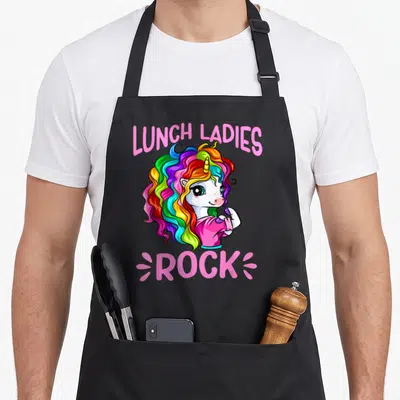 Rock unicorn lunch lady apron - Lunch Ladies Rock text surrounding a white unicorn with a rainbow mane in cartoon style — shown on a black cotton canvas apron against a white background