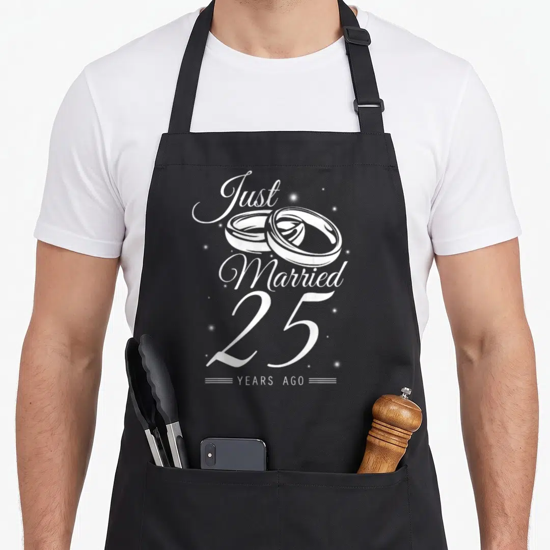 25th anniversary wedding apron - White Just Married 25 Years Ago text with two interlocking rings and sparkles — shown on a black cotton canvas apron against a white background