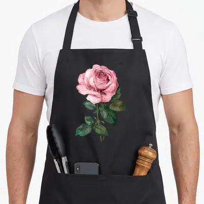 Funny flower rose apron - Realistic pink rose bloom with green leaves and stem on canvas — shown on a black cotton canvas apron against a white background