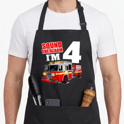 4th truck apron - SOUND THE ALARM I'M 4 text and red fire truck cartoon — shown on a black cotton canvas apron against a white background