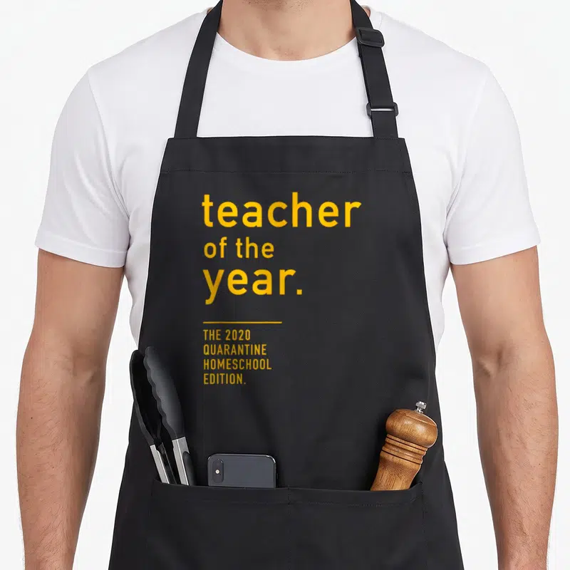 Quarantine teacher apron - Yellow stacked text reading teacher of the year 2020 quarantine homeschool edition — shown on a black cotton canvas apron against a white background
