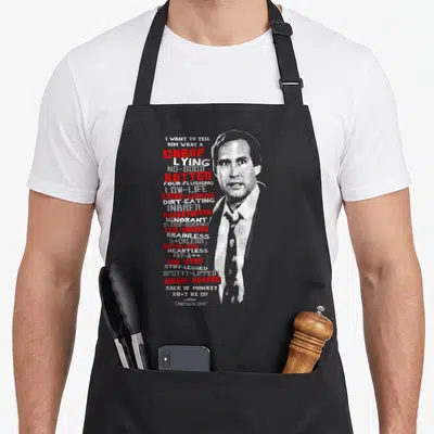 Vacation christmas apron - Man portrait with vertical list of insults in red and grey distressed text — shown on a black cotton canvas apron against a white background