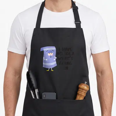 Towlie south apron - Confused purple towel character standing next to stacked text I HAVE NO IDEA WHAT'S GOING — shown on a black cotton canvas apron against a white background