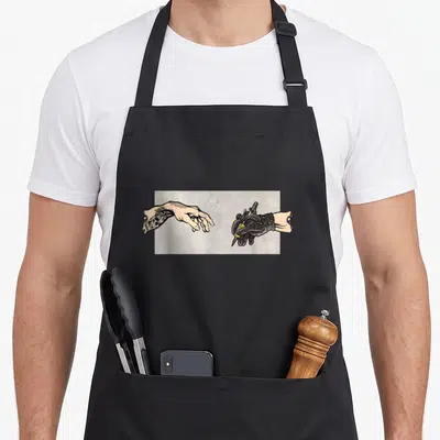 Gun artist tattoo apron - Tattooed hand reaching toward black gloved hand holding tattoo machine on grey background — shown on a black cotton canvas apron against a white background