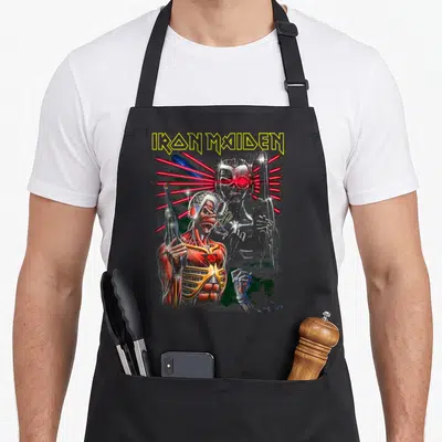 Terminate collection apron - Zombie cyborg with red lasers and IRON MAIDEN text on grey background — shown on a black cotton canvas apron against a white background