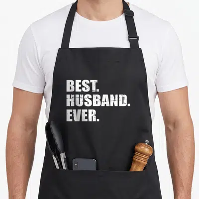 Spouse apron - White distressed BEST HUSBAND EVER text stacked on black fabric — shown on a black cotton canvas apron against a white background