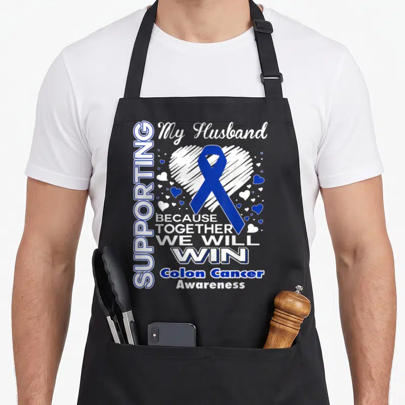 Colon husband apron - Blue ribbon over white heart with text supporting my husband colon cancer awareness — shown on a black cotton canvas apron against a white background