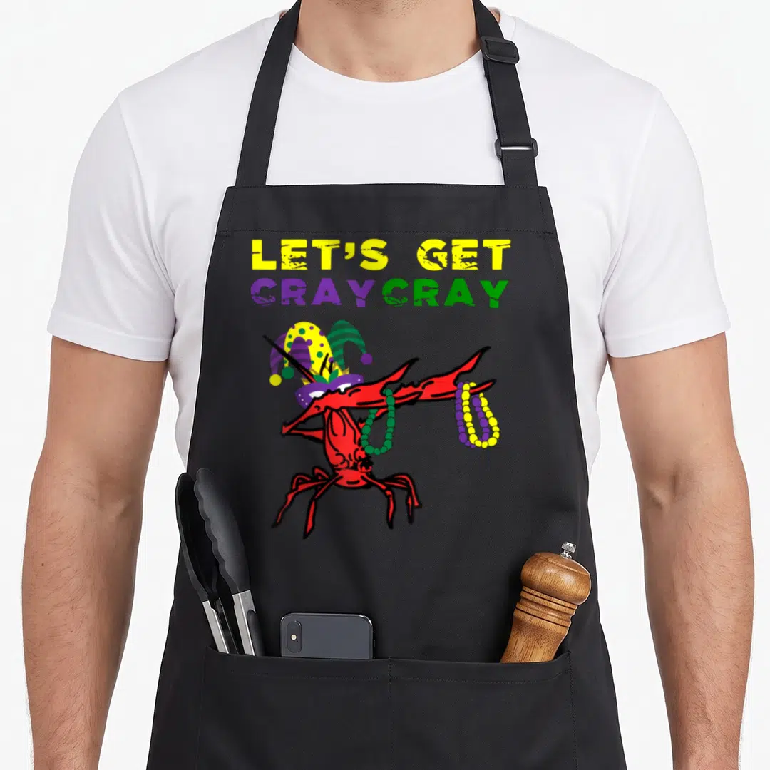Cray fat chef apron - Red crawfish in jester hat holding beads under distressed LET'S GET CRAYCRAY text — shown on a black cotton canvas apron against a white background