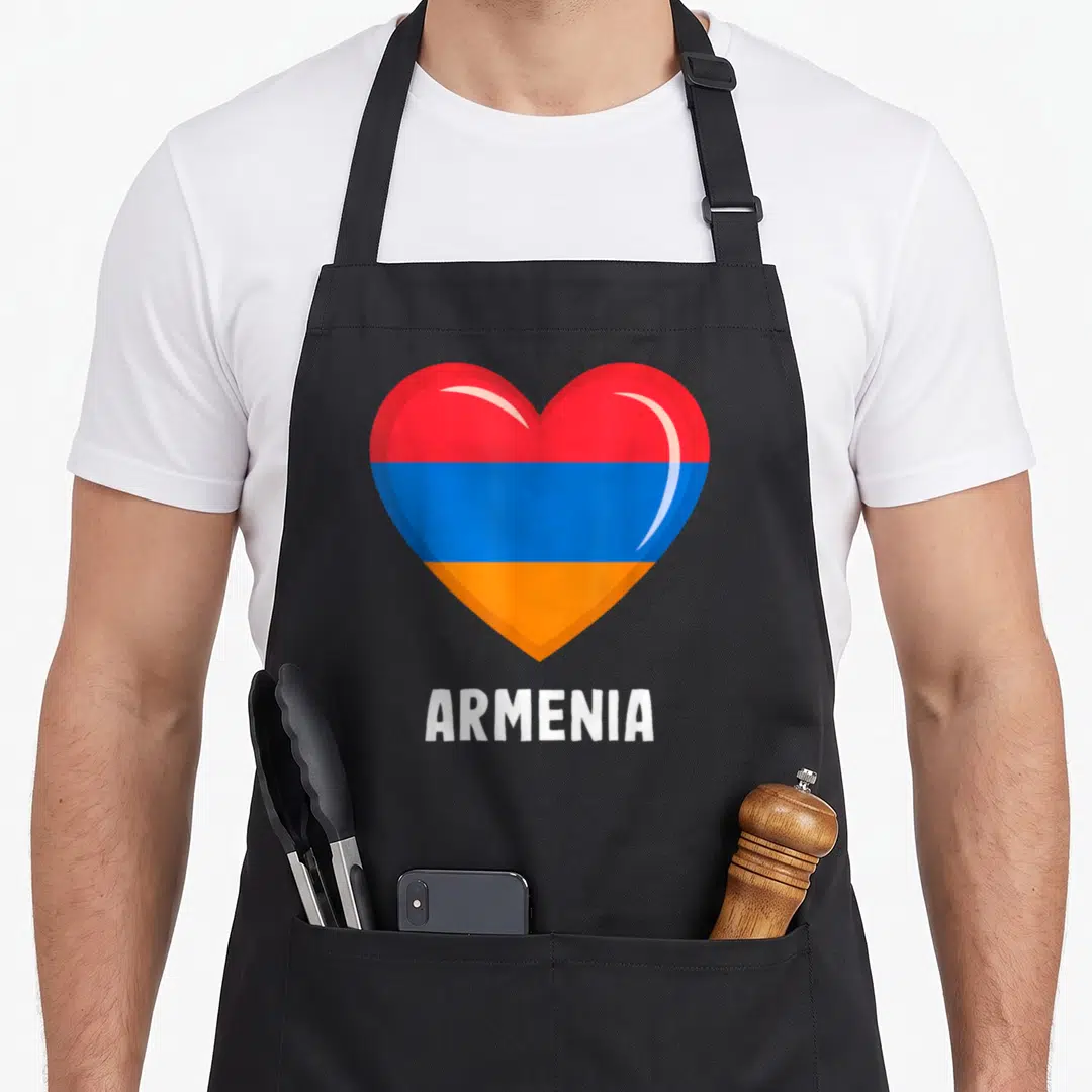 Flag armenian girl apron - Heart shape filled with red blue and orange horizontal stripes above white ARMENIA text — shown on a black cotton canvas apron against a white background