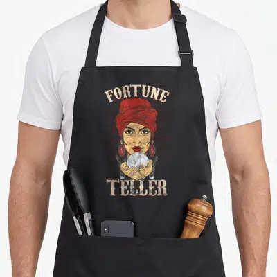 Fortune gypsy apron - Retro woman in red turban holding crystal ball with FORTUNE TELLER text — shown on a black cotton canvas apron against a white background