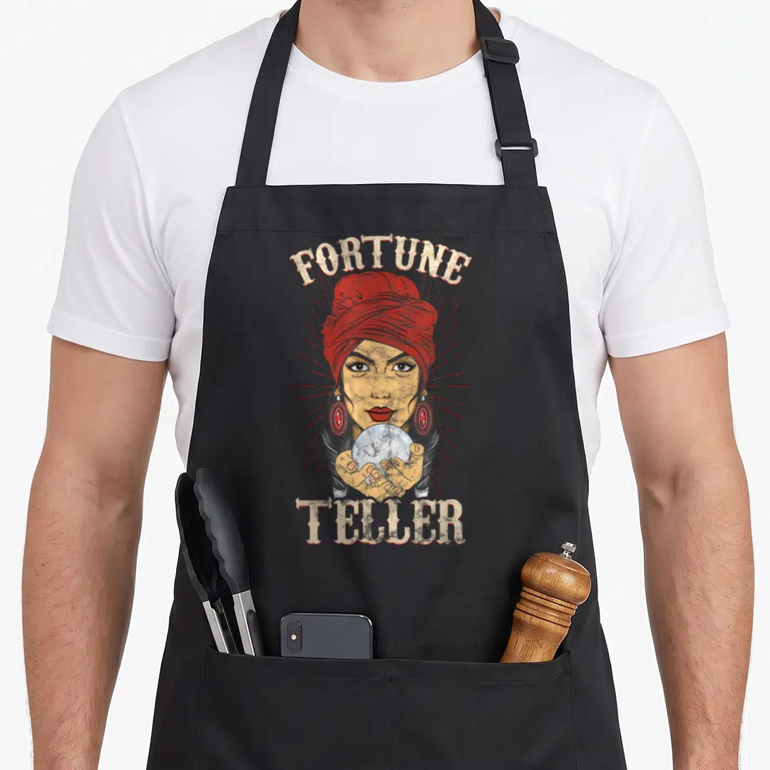 Fortune gypsy apron - Retro woman in red turban holding crystal ball with FORTUNE TELLER text — shown on a black cotton canvas apron against a white background