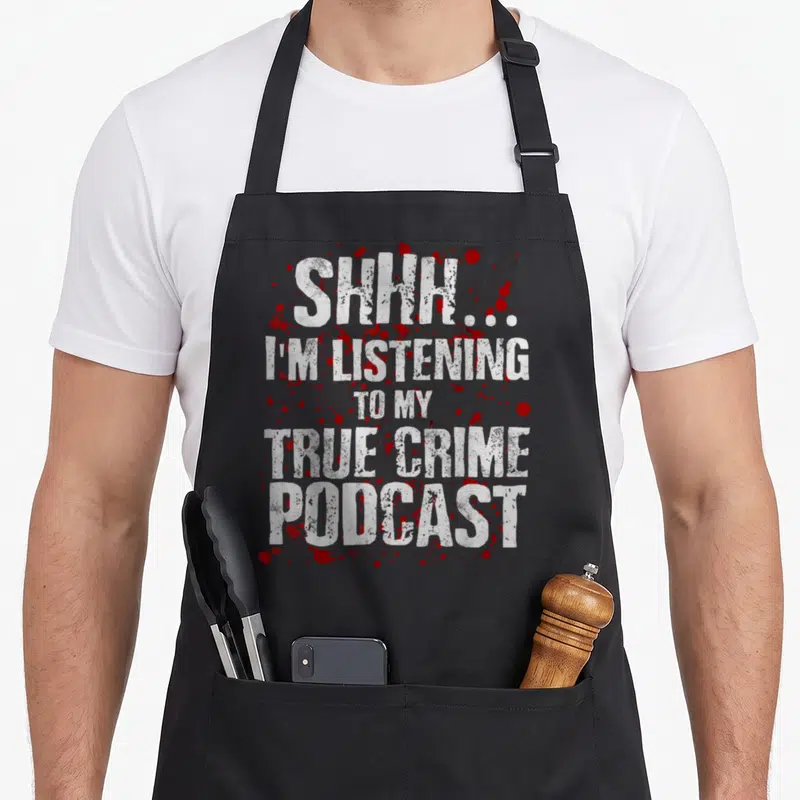 Murderino smiletodaytees apron - Distressed white text SHHH I'M LISTENING TO MY TRUE CRIME PODCAST over red blood — shown on a black cotton canvas apron against a white background