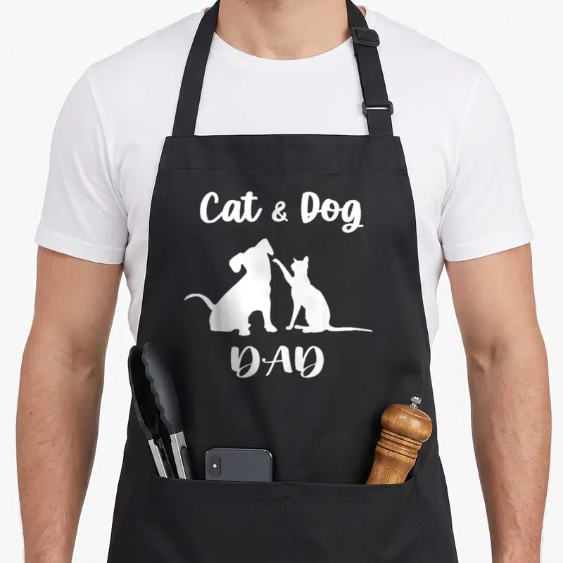 Animal puppy cat apron - White silhouettes of dog and cat facing each other with Cat & Dog DAD text — shown on a black cotton canvas apron against a white background