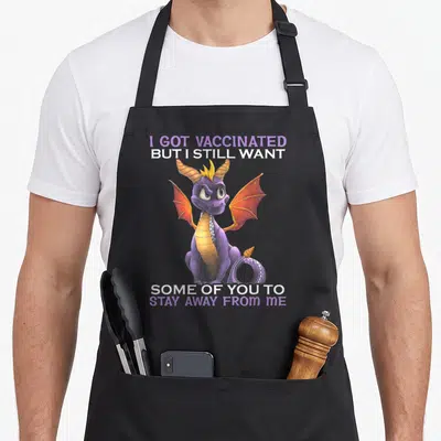 Vaccinated i love dragon apron - Purple cartoon dragon with orange wings and white text saying I got vaccinated but I — shown on a black cotton canvas apron against a white background