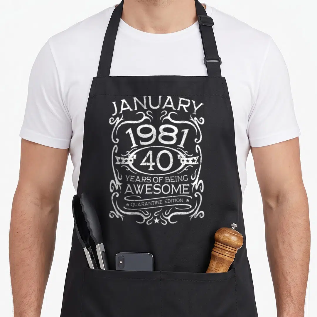 Funny january 40th birthday apron - White distressed text reading January 1981 40 Years of Being Awesome Quarantine — shown on a black cotton canvas apron against a white background