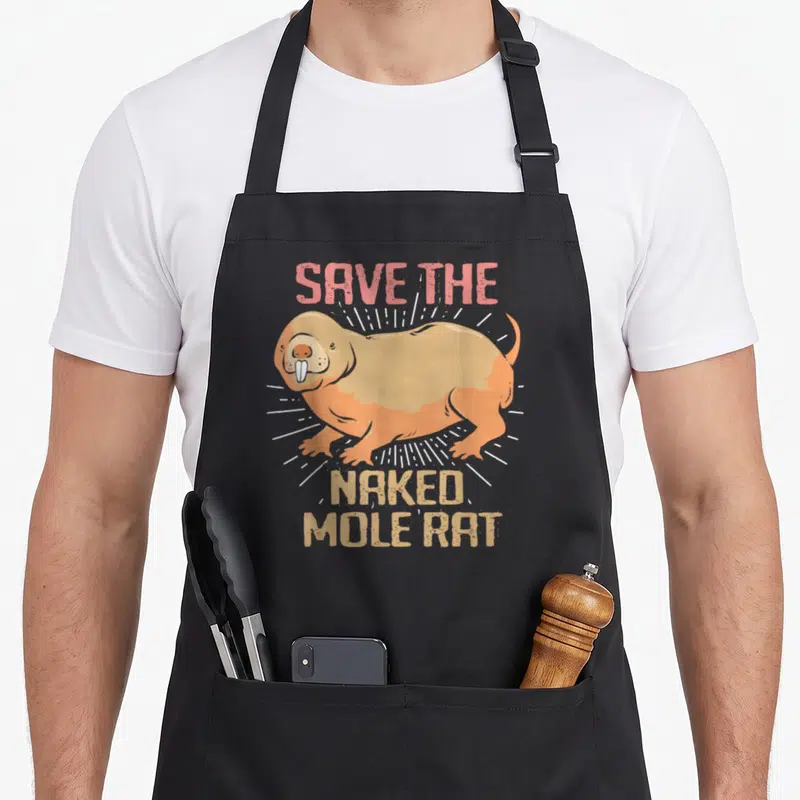 Naked rat mole apron - Cartoon tan and orange naked mole rat with SAVE THE NAKED MOLE RAT text and white rays — shown on a black cotton canvas apron against a white background