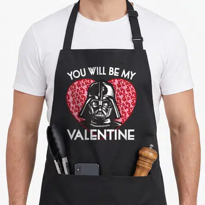 Vader valentine's day apron - Darth Vader head inside red heart with You Will Be My Valentine text — shown on a black cotton canvas apron against a white background