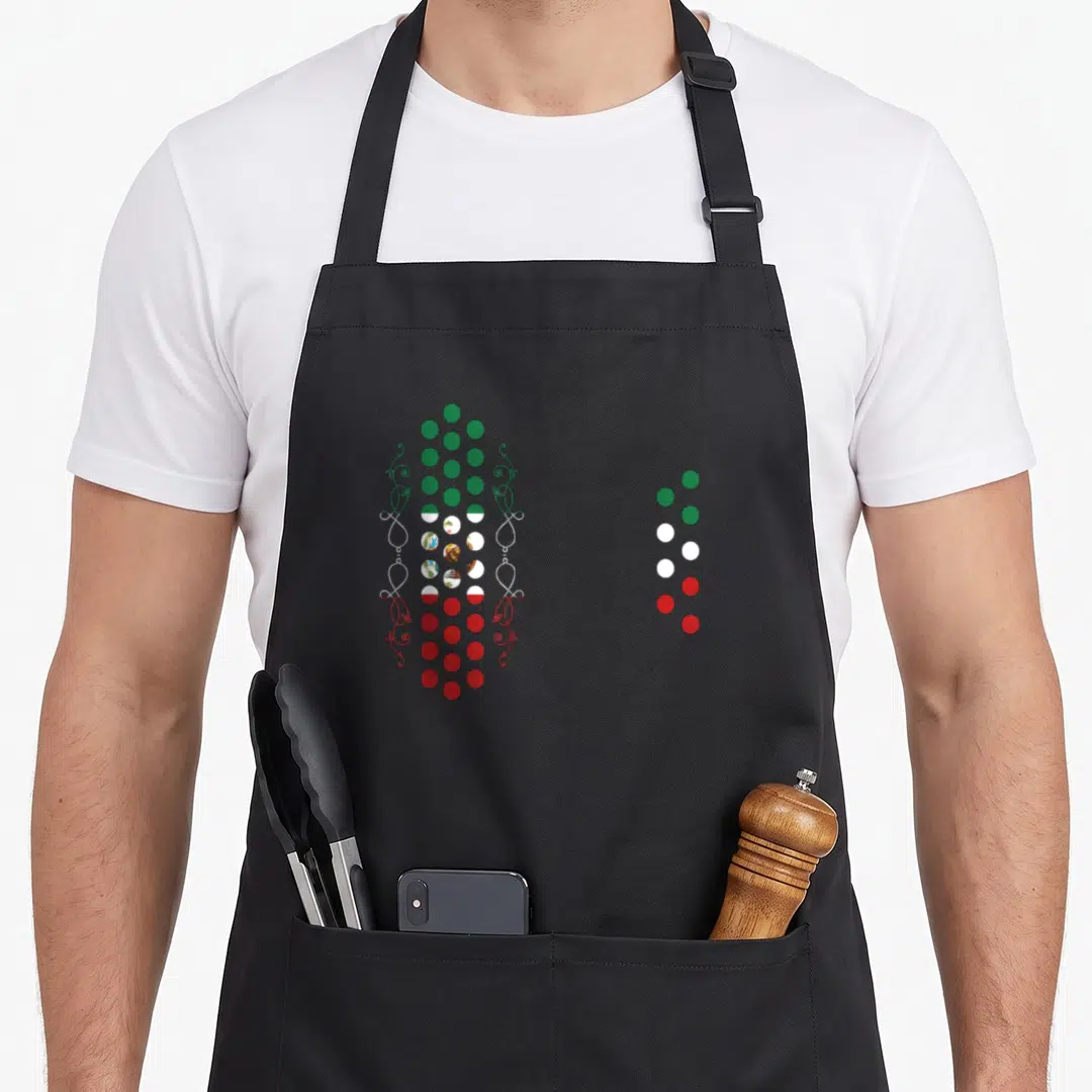 Air mexican apron - Vertical pattern of green white and red circles with eagle emblems and ornate scrollwork on sides — shown on a black cotton canvas apron against a white background