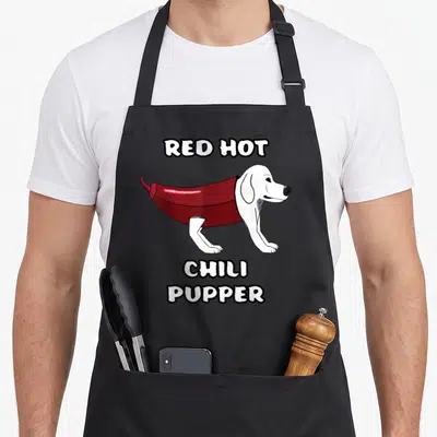 Rhcp chili pepper apron - Cartoon white dog wearing red chili costume with bold lettering — shown on a black cotton canvas apron against a white background