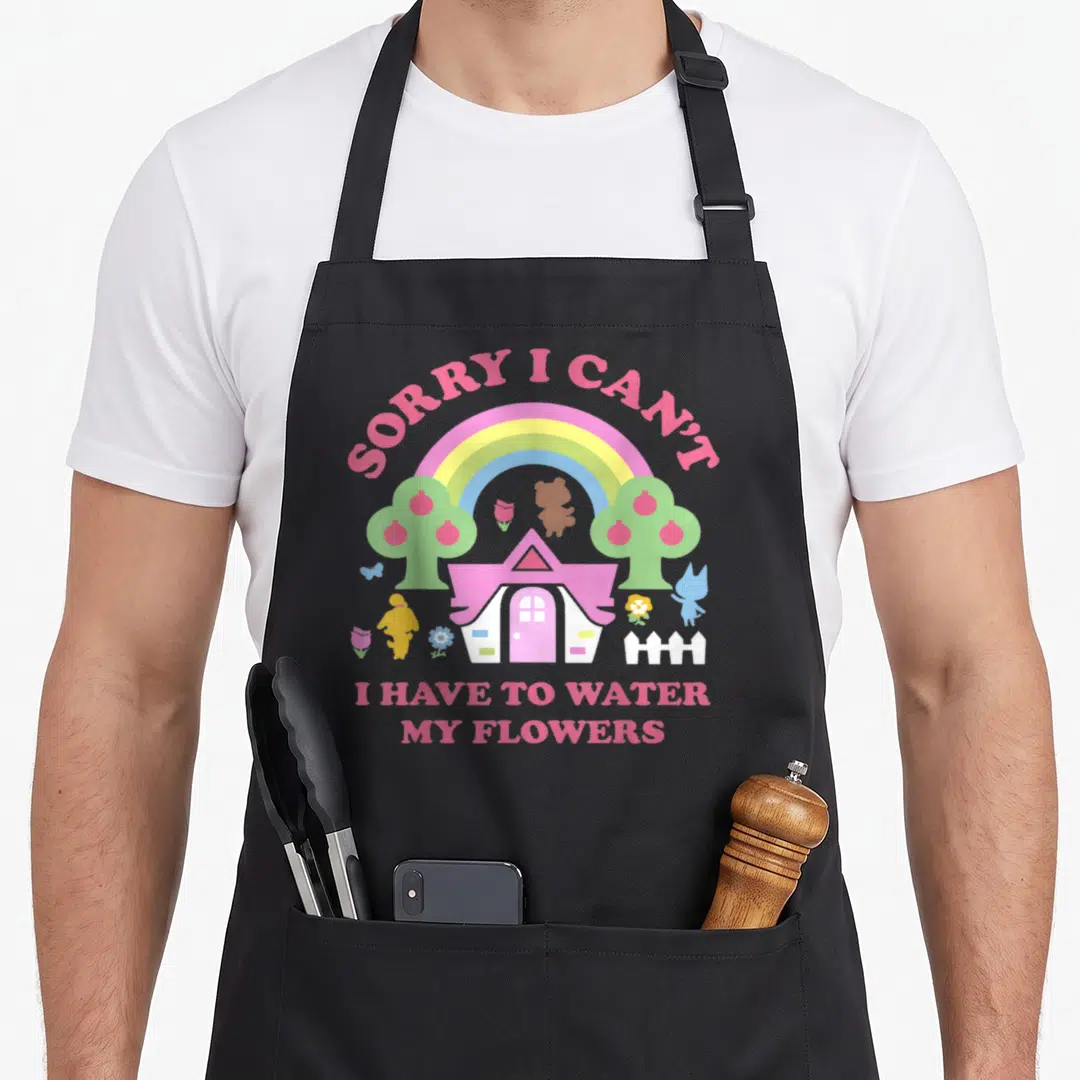Sorry animal apron - Cartoon house under pink rainbow with text Sorry I Can't I Have to Water My Flowers — shown on a black cotton canvas apron against a white background