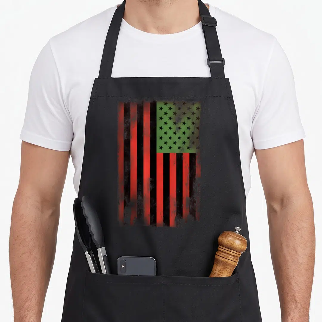Flag african print apron - Distressed red black and green flag with black stars on green background — shown on a black cotton canvas apron against a white background